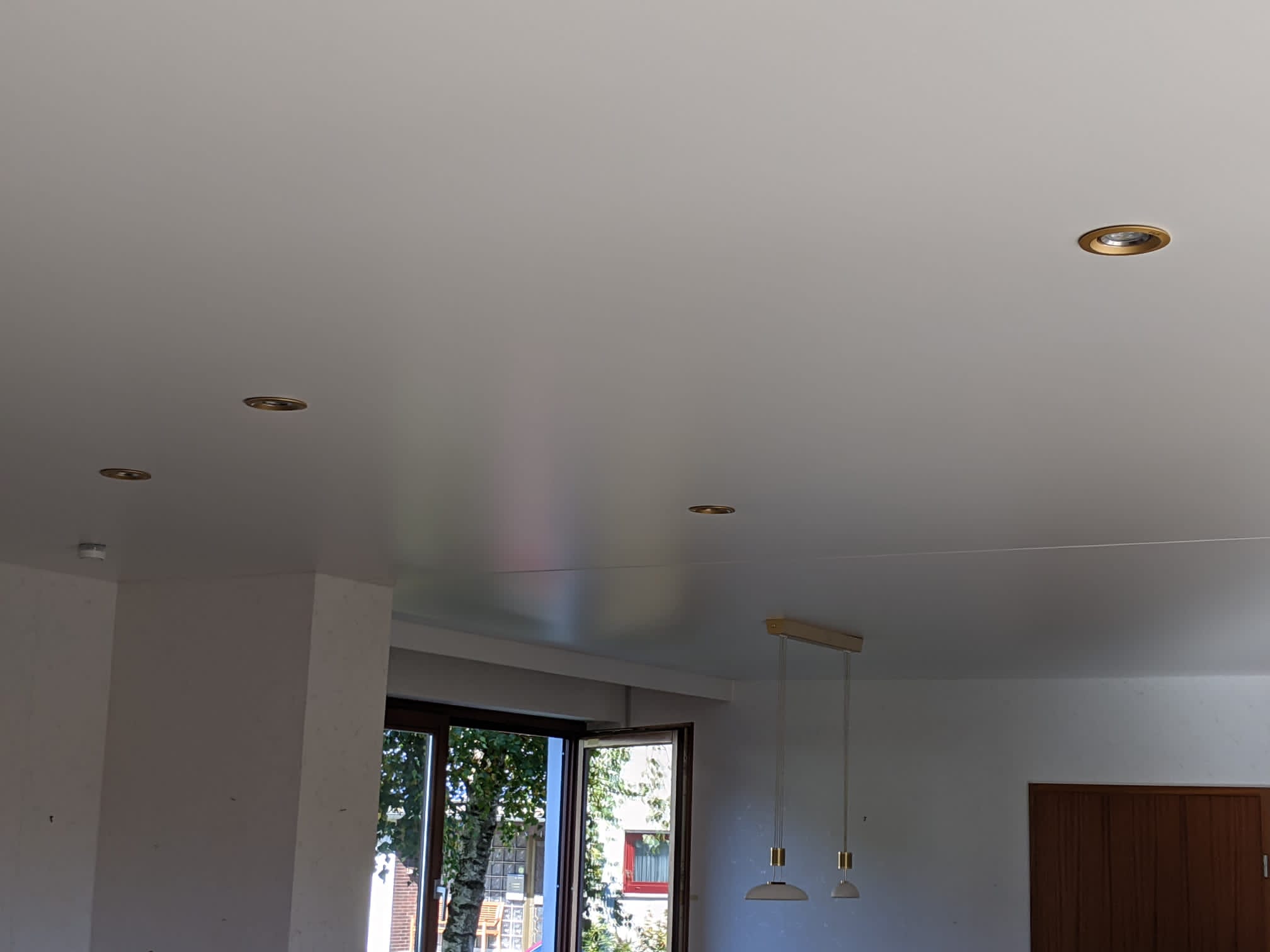 Spanndecke in Satin im Esszimmer mit goldenen Einbauleuchten. 